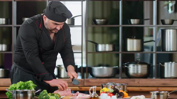 Bearded Chef in Uniform Chopping Delicate Meat Fillet