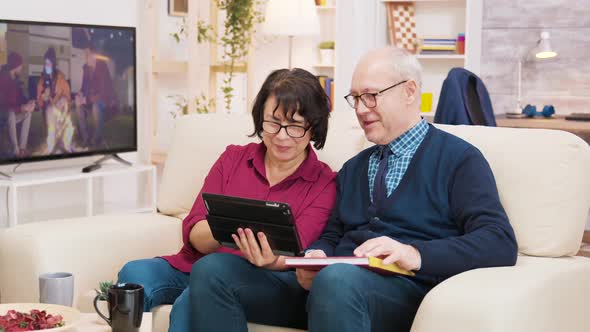 Old Couple Sitting on Sofa During a Video Call on Tablet