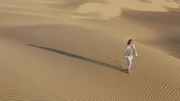 Nature Travel  Aerial Video. Young Woman Is Walking By the Sand Dunes