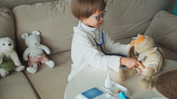 Little Doctor in Medical Coat with Stethoscope Play an Examination of Toy Bunny