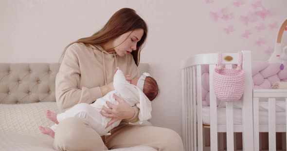 A Young Mother Lulls A Child In The Nursery