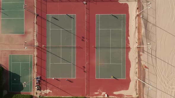 Two Tennis players enjoying a tennis match on the beach, with sand covering the court corner.