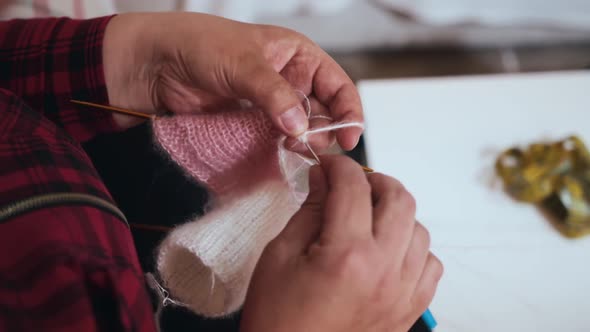 A Woman Knits Clothes for the Puppies with Knitting Needles