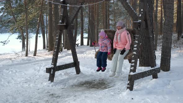 Child Swinging on a Swing with Mom in Winter Day