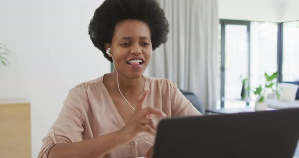 Happy african american woman sitting at table using laptop