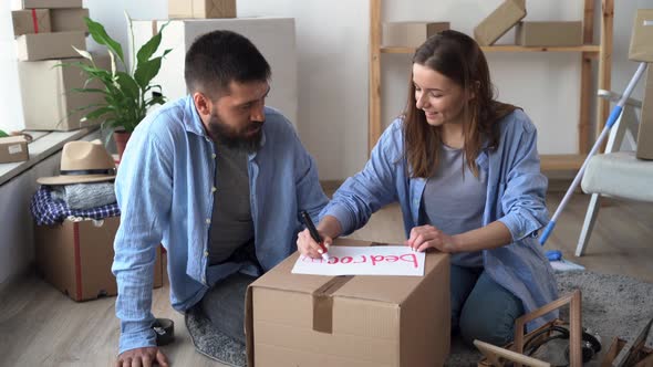 Young Married Couple Moves to a New House Packing Boxes with Things Carrying a Bedroom Box