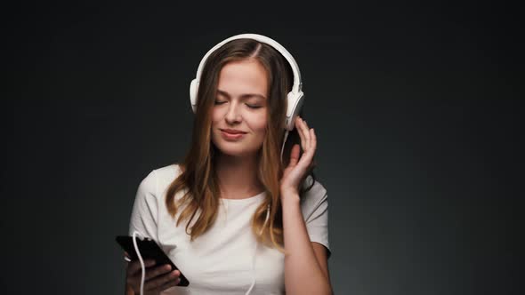 Beautiful Caucasian Woman with Headphones Dancing and Smiling at Camera