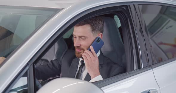 Happy Man in Suit Talking on Mobile While Examining Car