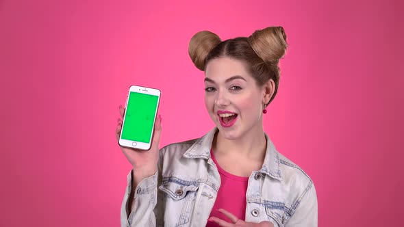 Girl Advertises the Phone. Pink Background. Slow Motion