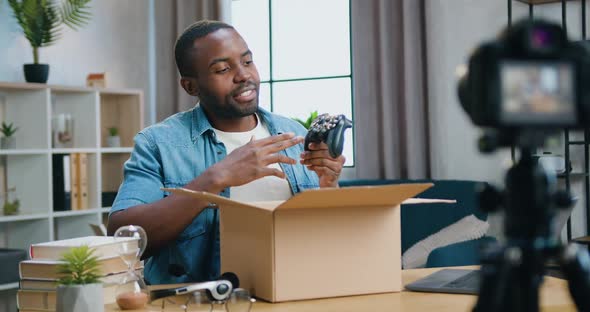 Blogger Sitting in front of Videocamera at Home and Telling About Bought Gamepad by Delivery