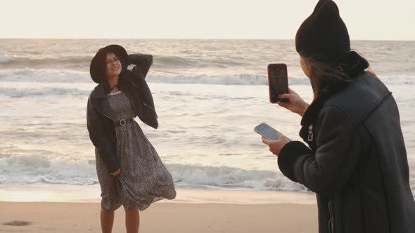 Couple of Beautiful Young Women Walking on the Beach on at Sunset