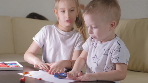 Two Child, Old Sister and Little Brother Playing with Plasticine at Home