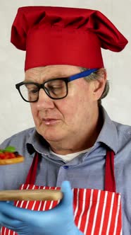 Senior Adult Chef Caucasian Ethnicity in Red Chef Hat Tasting with Enjoying Bruschetta