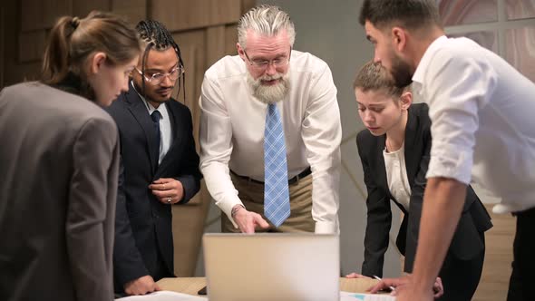 A mature solid gray-haired head of a firm discusses tasks with his subordinates