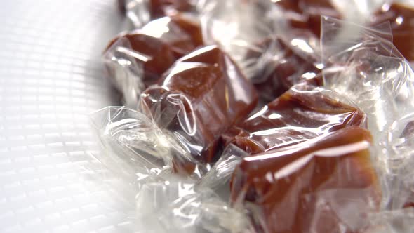 Toffee candy close up. Cellophane wrapped taffy candies on white saucer. Chocolate milky treat