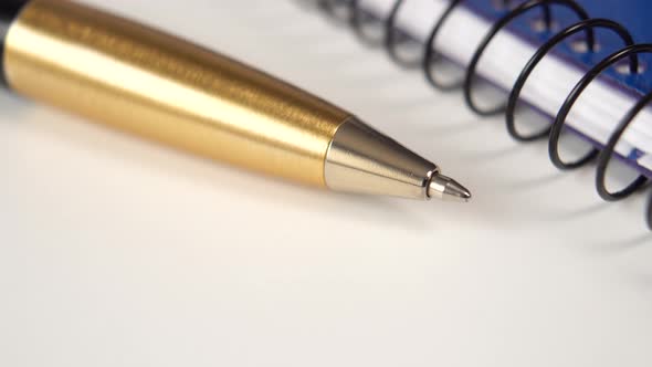 Close-up of a blue notebook and a golden pen on a gray office table.