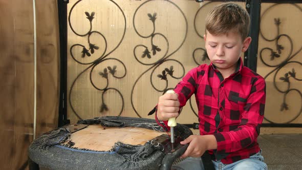 Boy Repairs Chair with a Screwdriver Unscrews Tightens the Screw Bolt