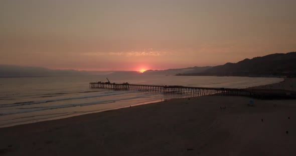 Amazing sunset over a pier, aerial shot with upwards motion. Pismo Beach, California.