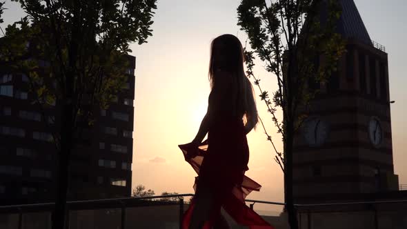 Silhouette Beautiful Young Girl Dancing on the Street of a Modern City in the Sunset Light. She Is