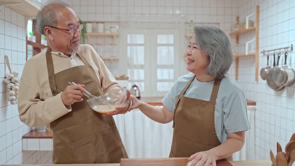 Asian happy senior older couple enjoy retirement life, cooking foods together in the kitchen at home