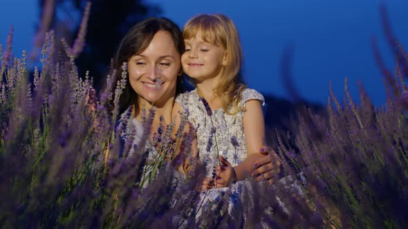 Mother and Girl Daughter Kid Kissing Laughing in Aromatic Flowers Lavender Field Garden at Night