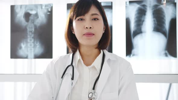 young Asia female doctor looking at camera and smiling while video conference call with patient.