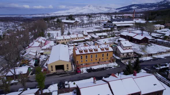 Low level push in aerial over the town of Pradera De Navalhorno in Spain to reveal the snow-covered