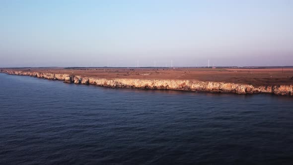 Drone top down aerial view of waves splash against rocky seashore, background. Flight over high clif