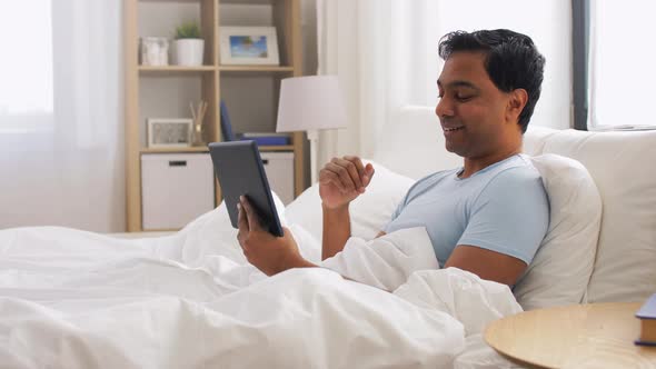 Happy Indian Man with Tablet Pc in Bed at Home