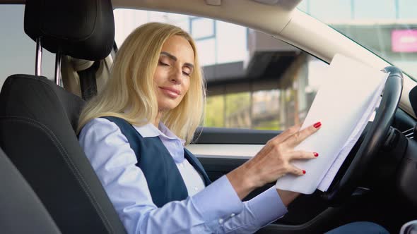 Portrait of a Confident Woman Sitting in a Car with Documents in a Business Suit Near a Modern