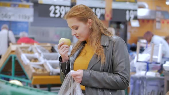 Pretty Young Beautiful Red Hair Woman Buys Food, Fruits, Apples in in the Market, in the Supermarket