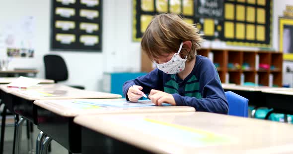 As children return to school during the Corona Virus, Covid 19 pandemic, a young boy wearing a mask