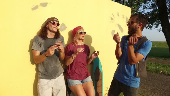 Woman and two men laughing and chilling after skateboarding