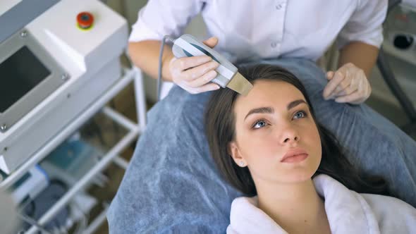 The Cosmetologist Makes the Procedure Ultrasonic Face Peeling of the Facial Skin of a Beautiful