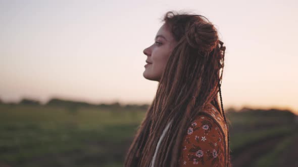 Portrait of an Attractive Hippie Woman with Dreadlocks in the Woods at Sunset Having Good Time