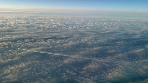 Incredible view from the cockpit of an airplane flying high above the clouds leaving a long white co