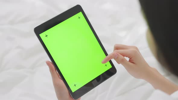 woman holding in hands a digital tablet with green screen for internet online.