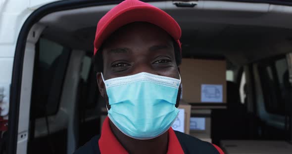 African male courier delivering packages with truck while wearing protective face mask