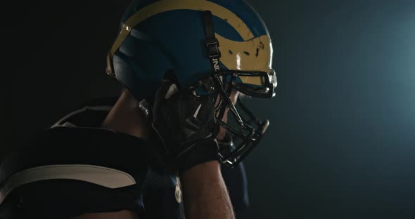 Portrait of American Football Sportsman Player Putting on and Tightening His Football Helmet on