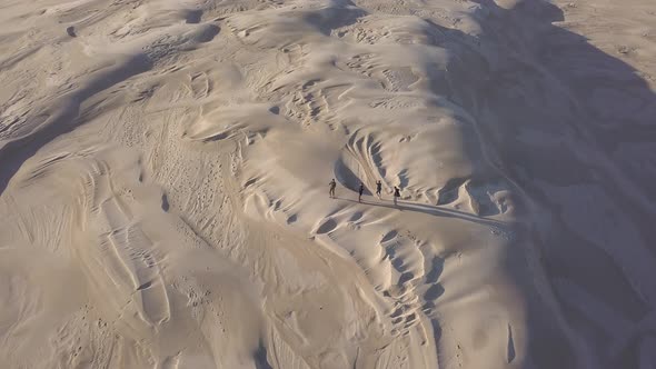 People walking across sand dunes in Australia, high aerial reveal