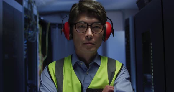 Portrait of asian male it technician wearing headphones by computer server