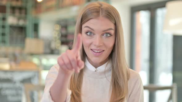 Portrait of Cheerful Young Woman Pointing with Finger