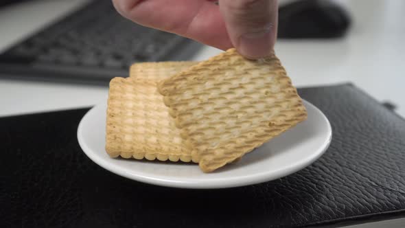 Shortbread snack on a leather notebook, computer equipment, keyboard and mouse in blur