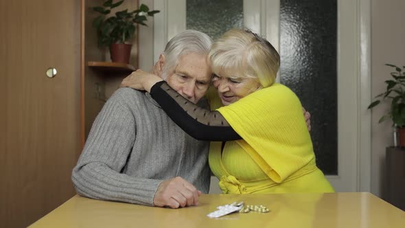 Old Senior Grandparents Looking at Pills, Tablets in a Blisters on Table at Home