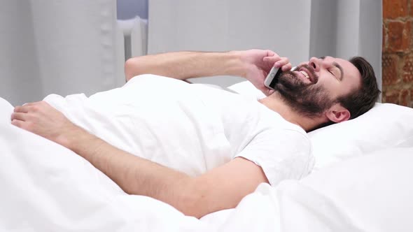 Beard Man in Bed Dialing Call and Talking on Phone