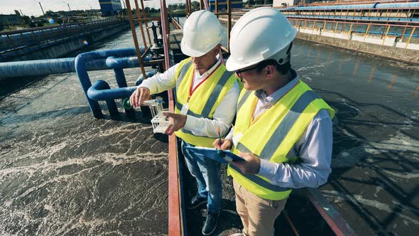 Two Specialists Taking Water Samples at a Sewage Treatment Plant