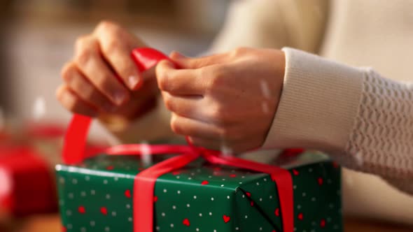 Hands Packing Christmas Gift and Tying Bow