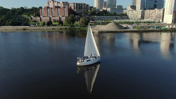 Aerial View of a White Sailing Yacht Sailing Near the Shore of the River