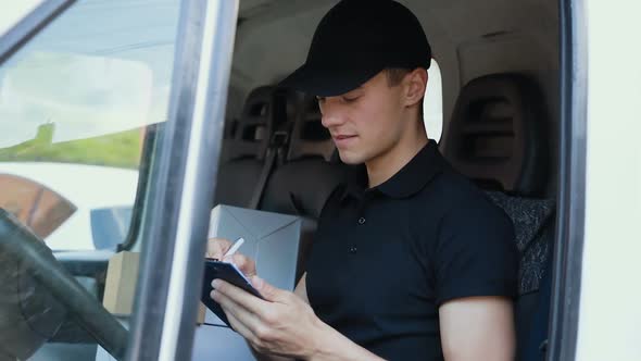 Delivery Courier In Car With Boxes Filling Delivery Document