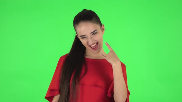 Portrait of Pretty Young Woman Is Making a Rock Gesture and Enjoying Life. Green Screen